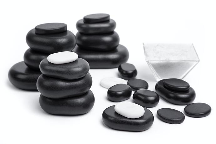 isolated massage stones set with salt; basalt spa stones on white background, close up